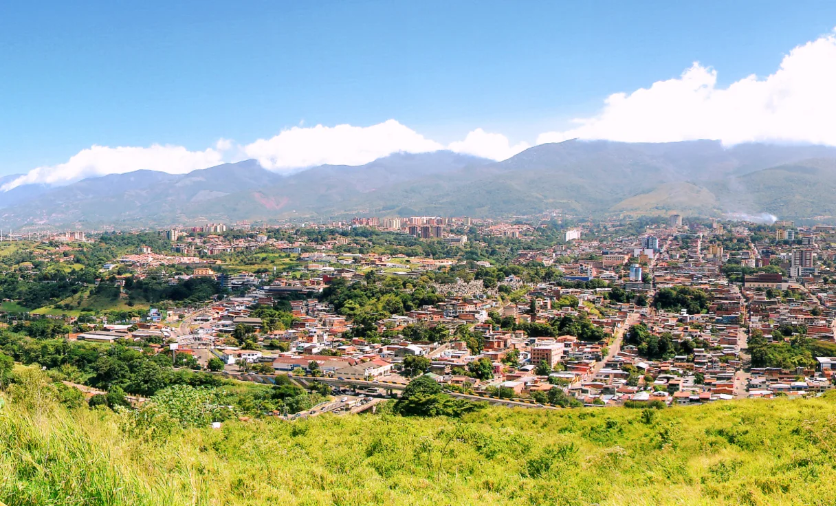 Urbanizaciones de San Cristóbal entre árboles, con la cordillera y nubes al fondo